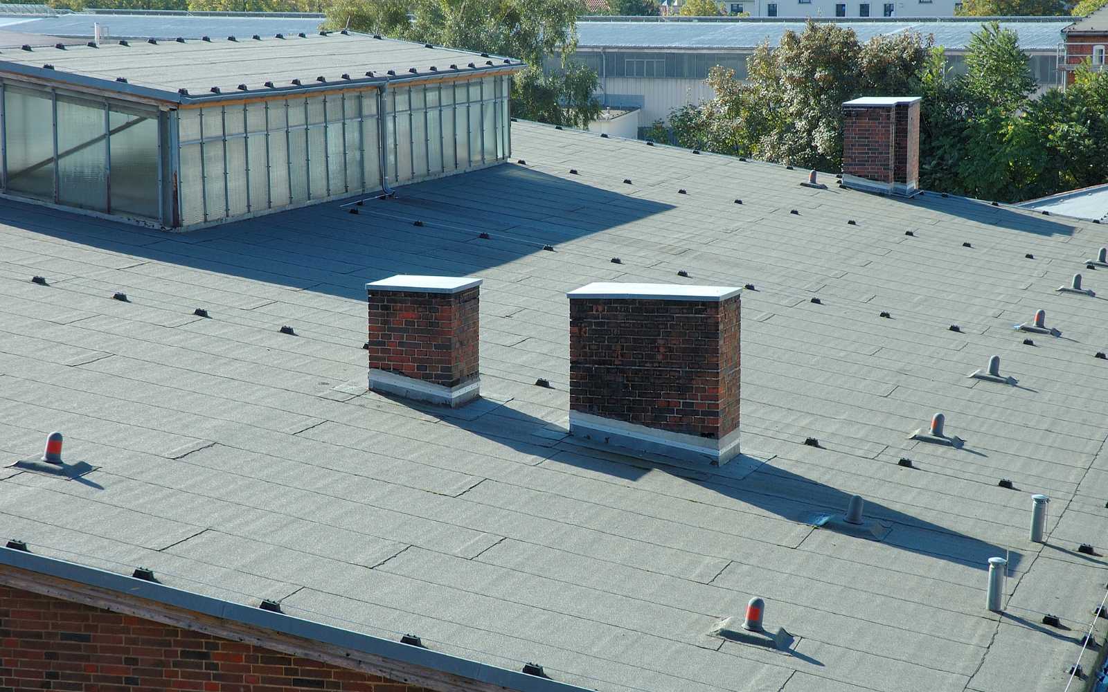 R&D ConstructionCommercial2 A high-angle view of a flat roof with several brick chimneys and vents.
